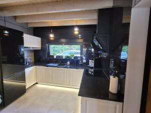 a kitchen with white cabinets and a black counter top at LoveLake dom z jacuzzi in Sława