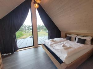 RadzyńにあるLoveLake dom z jacuzziのベッドルーム(大型ベッド1台、大きな窓付)