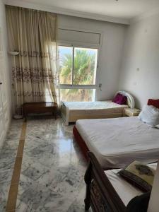 Habitación de hotel con 2 camas y ventana en CasaSlim Hammamet, en Hammamet