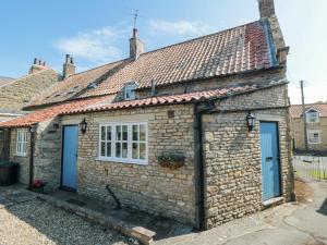 a stone cottage with blue doors and windows at Chapel Cottage in Ebberston