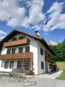 サン・ヴィート・ディ・カドーレにあるDeliziosa mansarda con vista Dolomitiの白い建物(木製バルコニー付)