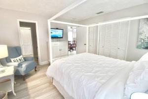 - une chambre blanche avec un grand lit et une télévision dans l'établissement Coastal Village Retreat, à Jupiter