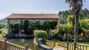 a house with a pond in front of a fence at Eco molino rural in Santa Eulalia