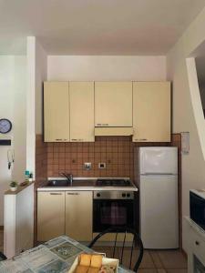 uma cozinha com armários brancos, um fogão e um frigorífico em Fonzi’s House em La Spezia