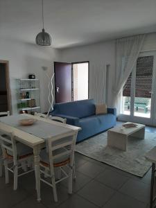 ein Wohnzimmer mit einem blauen Sofa und einem Tisch in der Unterkunft Appartamento a pochi passi dal mare in Porto Cesareo