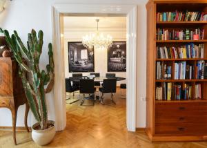 Neoclassical Luxury Apartment Ljubljana في ليوبليانا: غرفة طعام مع طاولة ورف كتاب مع كتب