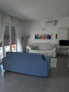ein Wohnzimmer mit einem blauen Sofa und einem Bett in der Unterkunft Appartamento a pochi passi dal mare in Porto Cesareo