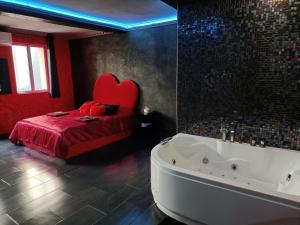 a bedroom with a tub and a bed with a red blanket at L'instant romance Le Romantique in Castelnaudary