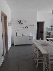 eine weiße Küche mit einem Tisch und weißen Schränken in der Unterkunft Appartamento a pochi passi dal mare in Porto Cesareo