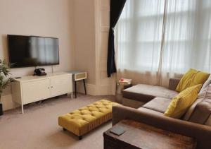 a living room with a couch and a flat screen tv at 3 Sheets To The Wind, Boutique Holiday Apartment in Torquay in Torquay