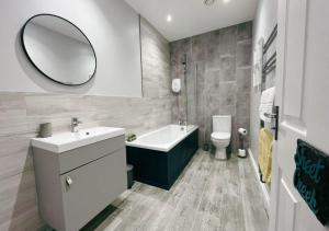 a bathroom with a sink and a toilet and a mirror at 3 Sheets To The Wind, Boutique Holiday Apartment in Torquay in Torquay