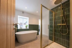 une salle de bain avec baignoire et douche en verre dans l'établissement Stylish, comfortable, convenient!, à Bala