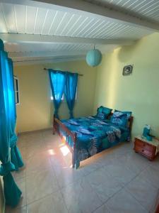 1 dormitorio con 1 cama en una habitación con cortinas azules en Cocon Tropical en Vieux-Habitants