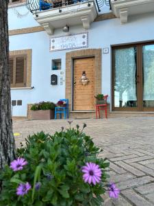 una puerta de un edificio con flores púrpuras delante de él en B&B Savoia San Salvo, en San Salvo