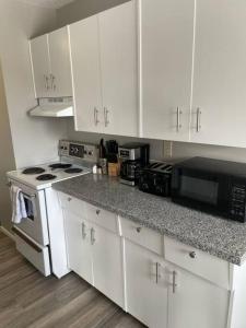 uma cozinha com armários brancos, um fogão e micro-ondas em Exquisite 2 Bedroom Apartment em Camrose