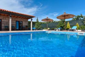 una piscina con sombrillas y una casa en Feel Discovery Maçã Douro, en Armamar