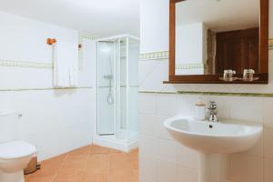 a white bathroom with a sink and a shower at Casa Do Romualdo in Vilela