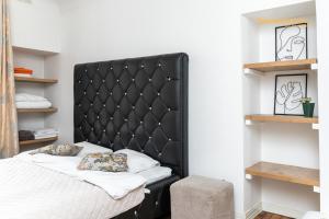 a bed with a black padded headboard in a bedroom at Luxury Suites - Old Town Sauna Str in Tallinn