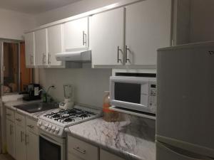 a kitchen with white cabinets and a stove and a microwave at Lindo departamento con 2 cuartos y excelente ubicacion. in Hermosillo