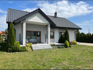 a small white house with a grass yard at Beztroski Zakątek in Nowe Guty