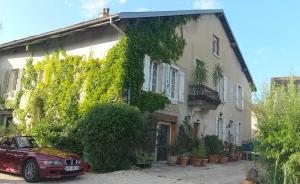 a red car parked in front of a building at A la Grenouille du Jura in Bellignat