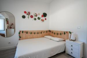 een slaapkamer met een wit bed en een spiegel bij Casa das Andorinhas in Sintra