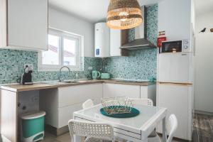 uma cozinha com armários brancos e uma mesa com cadeiras em Casa das Andorinhas em Sintra