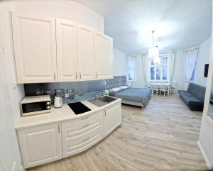 a kitchen with white cabinets and a living room at Viator in Ustka