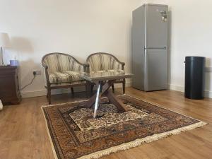 a living room with a table and two chairs and a refrigerator at Cosy Studio Flat at Gants Hill Station, Ilford, Essex, London in Wanstead