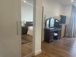 a bedroom with a mirror and a dresser and a bed at Cosy Studio Flat at Gants Hill Station, Ilford, Essex, London in Wanstead