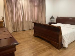 a bedroom with a bed with a wooden floor and curtains at Cosy Studio Flat at Gants Hill Station, Ilford, Essex, London in Wanstead
