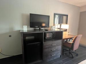 a hotel room with a desk with a tv and a deskablish at Days Inn & Suites by Wyndham Monroe in Monroe
