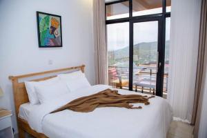 een deken op een bed in een kamer met een raam bij Nzuri Nest Apartments Zuba in Kigali