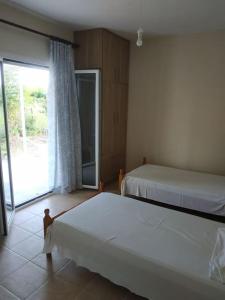 - une chambre avec 2 lits et une grande fenêtre dans l'établissement Εξοχική Κατοικία - Αγιόκαμπος, à Loutra Edipsou