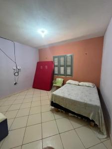 - une chambre avec un lit et une chaise rouge dans l'établissement Hospedagem da Cleidiane, à Icapuí