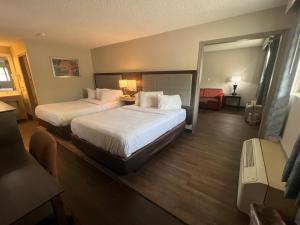 a hotel room with two beds and a chair at Days Inn & Suites by Wyndham Monroe in Monroe