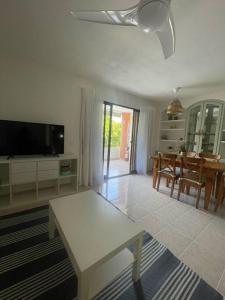 ein Wohnzimmer mit Fernseher und Tisch in der Unterkunft Precioso duplex y espacioso en la playa de Gandía in Playa de Gandia