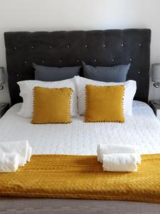 Una cama grande con almohadas amarillas y blancas. en Alexia Room, en Funchal