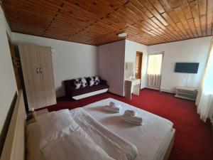 Un dormitorio con una cama blanca y un sofá. en Vila Vitalis, en Predeal