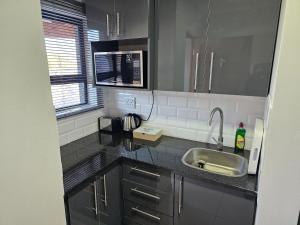 a kitchen with a sink and a microwave at Intuthuzelo on Bramleigh in East London