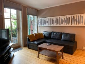 a living room with a black leather couch and a coffee table at Lovely condo with fireplace & parking@city center in Drammen