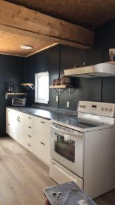 a kitchen with white appliances and a black wall at Gîte de la Montagne Enchantée in Metabetchouan