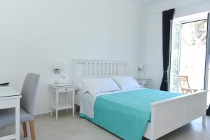 Un dormitorio blanco con una cama azul y una ventana en Addore Re Mare en Santa Maria di Castellabate