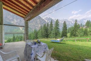 a table and chairs on a patio with a view of mountains at Baita Margherita - Val Veny in Courmayeur