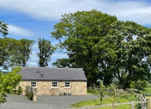 a stone barn in a field with trees at Stay on the Hill - Self Catered Cottages Laverick and Bothy in Hexham