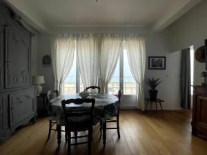 a dining room with a table and chairs and a window at Vue mer, 2 chambres et 2 SDB. in Saint-Valery-en-Caux