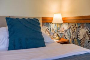 a bed with a blue pillow next to a lamp at Hotel Arcus Garden in Bratislava