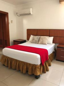 1 dormitorio con 1 cama grande con manta roja en Hoteles en Guayaquil - Suites Guayaquil Cerca del Aeropuerto en Guayaquil