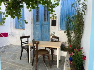 stół i krzesła przed niebieskimi drzwiami w obiekcie Dream House Little Villa - Amorgos w mieście Amorgós