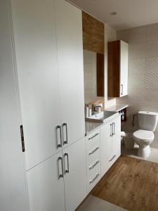 a bathroom with white cabinets and a toilet at Beztroski Zakątek in Nowe Guty
